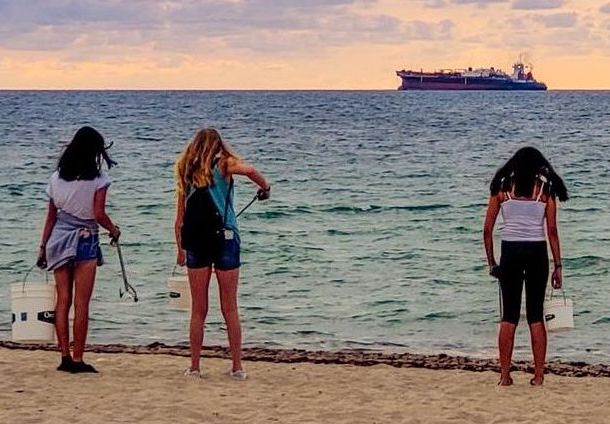 Young volunteers at the Fort Lauderdale beach picking up cigarette butts one at a time.